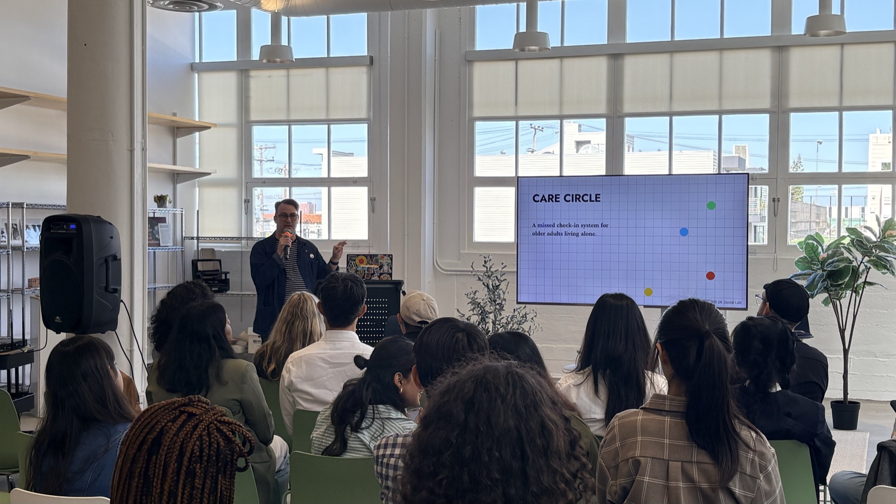 Josh presenting Care Circle to a seated audience at IDEO, with the title slide on screen