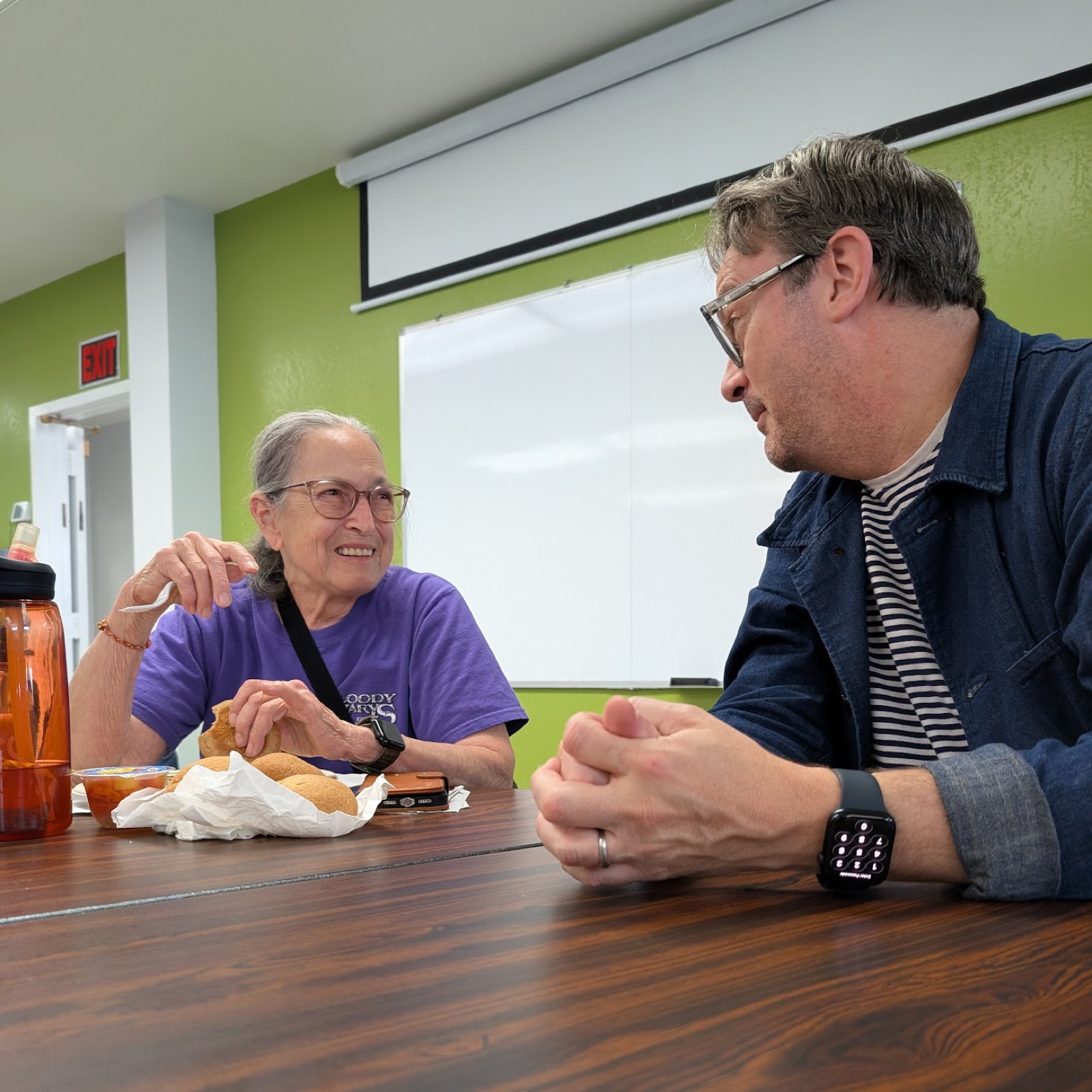 Josh in conversation with an older adult across a table at the Richmond Senior Center